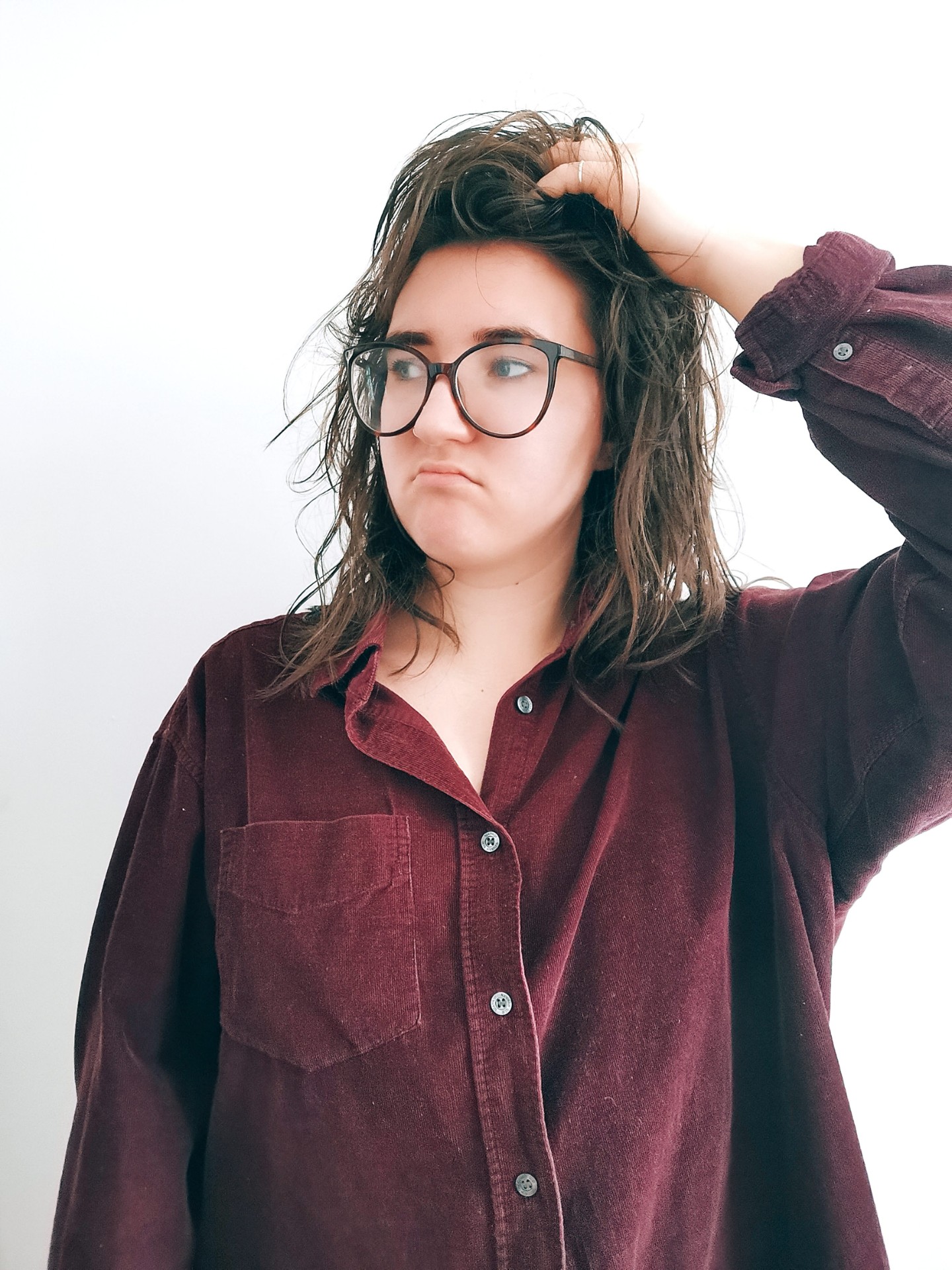 girl in a burgundy shirt looking unhappy with wet hair before the curly girl method