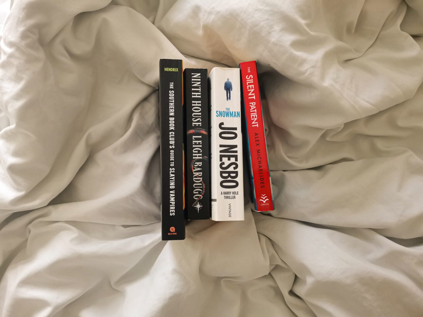 Landscape image of my four November 2023 TBR books propped against one another on white sheets