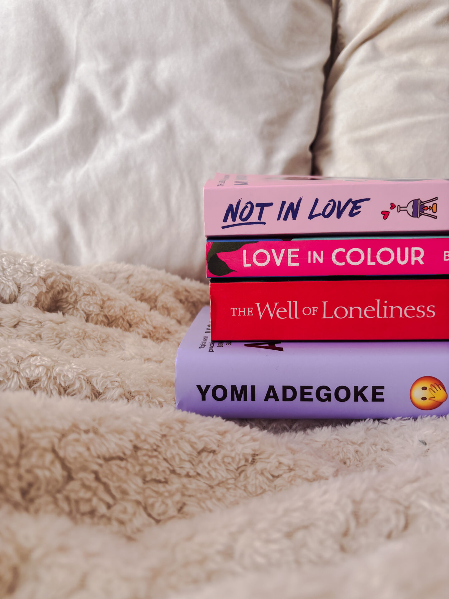 a stack of four books on top of a pink blanket